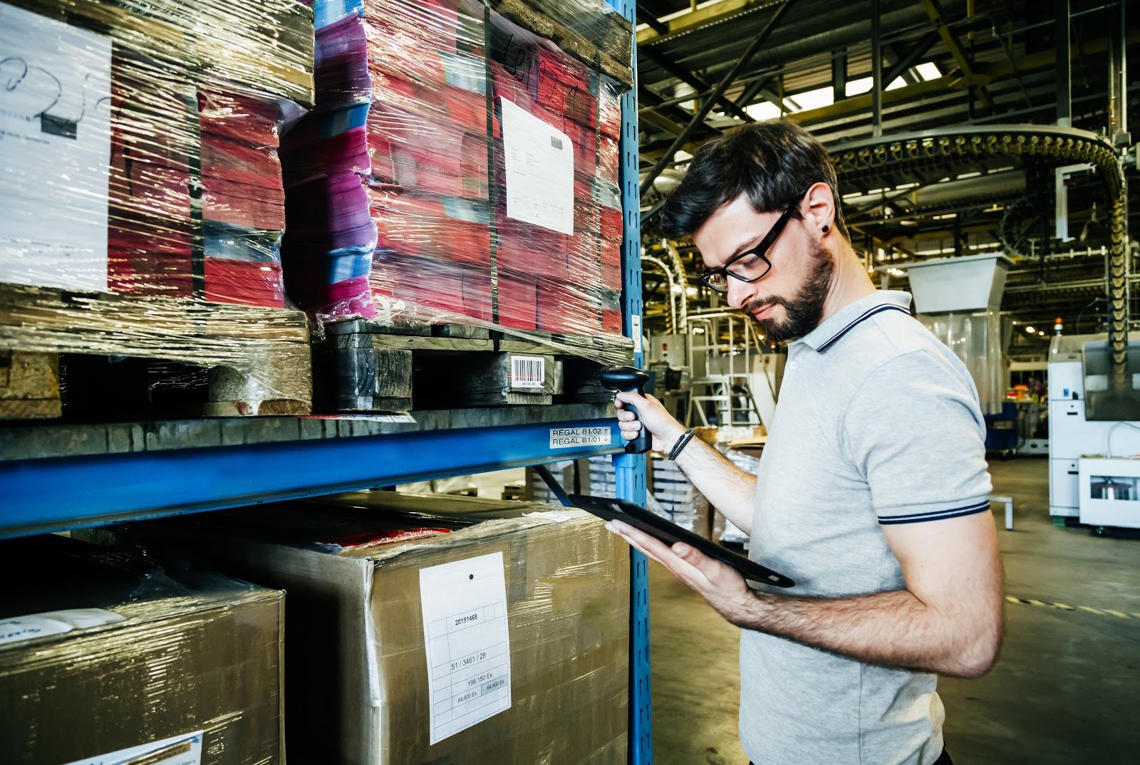 bearded man looks at his clipboard in a warehouse.jpg